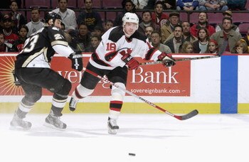 EAST RUTHERFORD, NJ - DECEMBER 6:  Center Sergei Brylin #18 of the New Jersey Devils chases down the puck while being defended by left wing Steve McKenna #23 of the Pittsburgh Penguins at Continental Airlines Arena on December 6, 2002 in East Rutherford, 