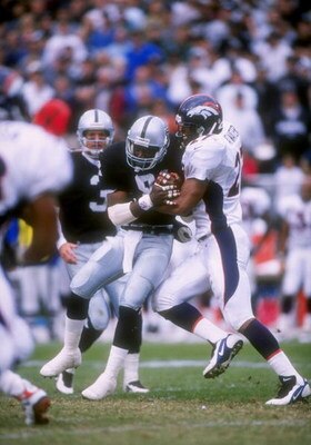 19 Oct 1997: Safety Steve Atwater of the Denver Broncos (right) tries to bring down wide receiver Tim Brown of the Oakland Raiders (center) during a game at the Oakland Alameda County Coliseum in Oakland, California. The Raiders won the game 28-25.