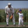 DYERSVILLE, IA - AUGUST 25: A 'ghost player' recreating the role of Chicago White Sox legend Shoeless Joe Jackson plays ball with a young tourist at the baseball field created for the motion picture 'Field of Dreams' on August 25, 1991 in Dyersville, Iowa
