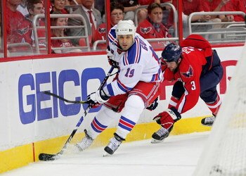 WASHINGTON - APRIL 28: Scott Gomez #19 of the New York Rangers skates the puck past Tom Poti #3   of the Washington Capitals during Game Seven of the Eastern Conference Quarterfinal Round of the 2009 Stanley Cup Playoffs on April 28, 2009 at the Verizon C