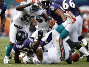 MIAMI - JANUARY 04:  Le'Ron McClain #33 of the Baltimore Ravens fumbles on a first quarter run while being tackled by Paul Soliai #96 and Joey Porter #55 of the Miami Dolphins during their AFC Wild Card playoff game on January 4, 2009 at Dolphin Stadium i