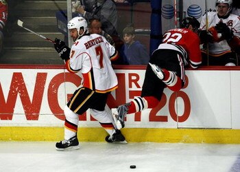CHICAGO - APRIL 16:  Todd Bertuzzi #7 of the Calgary Flames checks Troy Brouwer #22 of the Chicago Blackhawks into the Flames' bench during Game One of the Western Conference Quarterfinals of the 2009 Stanley Cup Playoffs on April 16, 2009 at the United C