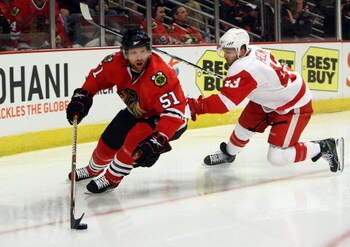 CHICAGO - MAY 22:  Brian Campbell #51 of the Chicago Blackhawks skates with the puck against Darren Helm #43 of the Detroit Red Wings during Game Three of the Western Conference Championship Round of the 2009 Stanley Cup Playoffs on May 22, 2009 at the Un