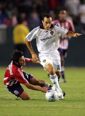 CARSON, CA - AUGUST 14:  Landon Donovan #10 of the Los Angeles Galaxy dribbles the ball past a falling Paulo Nagamura #5 of CD Chivas USA in the second half of their MLS match at the Home Depot Center on August 14, 2008 in Carson, California. The Galaxy a