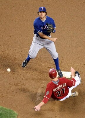 PHOENIX - JUNE 23:  Infielder Ian Kinsler #5 of the Texas Rangers throws over the sliding Mark Reynolds #27 of the Arizona Diamondbacks to complete a double play during the major league baseball game at Chase Field on June 23, 2009 in Phoenix, Arizona.   