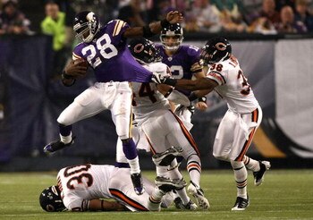 MINNEAPOLIS - NOVEMBER 30:  Adrian Peterson #28 of the Minnesota Vikings leaps over  Mike Brown #30 of the Chicago Bears as Danieal Manning #38 grabs his jersey at the Metrodome on November 30, 2008 in Minneapolis, Minnesota.  (Photo by Jonathan Ferrey/Ge
