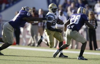 SEATTLE - SEPTEMBER 23:  Running back Chris Markey #28 of the UCLA Bruins rushes against Brandon Ala #41 and Roy Lewis #28 of the Washington Huskies on September 23, 2006 at Husky Stadium in Seattle Washington. The Huskies defeated the Bruins 29-19.  (Pho