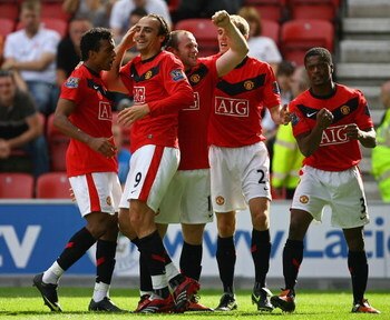 WIGAN, ENGLAND - AUGUST 22:  Dimitar Berbatov of Manchester United celebrates with his team mates after scoring the second goal during the Barclays Premier League match between Wigan Athletic and Manchester United at the DW Stadium on August 22, 2009 in W