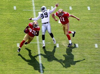 SAN FRANCISCO - AUGUST 22:  Alex Smith #11 of the San Francisco 49ers blocks against Greg Ellis #99 of the Oakland Raiders as Arnaz Battle #83 runs on a reverse during a preseason game on August 22, 2009 at Candlestick Park in San Francisco, California.  